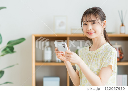 リビングでスマホを操作する女性。 112067950
