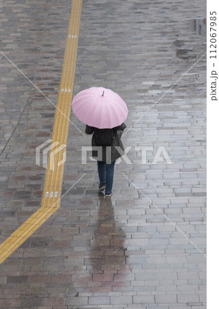 雨降りの日の都心。傘をさした人が歩く。大阪梅田で撮影 112067985