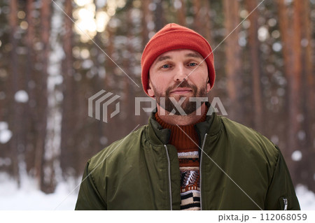 Portrait of young Caucasian man wearing warm clothes standing in forest on winter day Portrait of young Caucasian man wearing warm clothes standing in forest on winter day 112068059