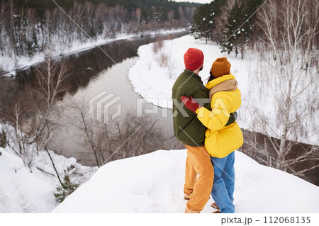 High angle view of unrecognizable romantic couple standing on cliff on winter day enjoying picturesque view High angle view of unrecognizable romantic couple standing on cliff on winter day enjoying picturesque view 112068135