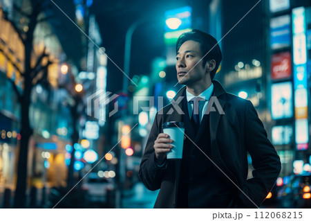 夜の街並みでコーヒーを飲むビジネスマン 112068215