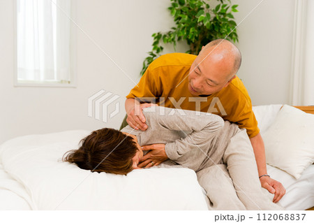 病気で急な胸の激痛の発作を発症した50代から60代のシニアの女性とそれを見つけてあせる夫 112068837