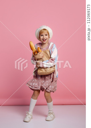 Joyful girl jumping with a bag of bread on a pink background 112069173