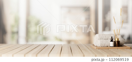 A spa set on a wooden tabletop with a blurred background of a contemporary, spacious bathroom. A spa set on a wooden tabletop with a blurred background of a contemporary, spacious bathroom. 112069519