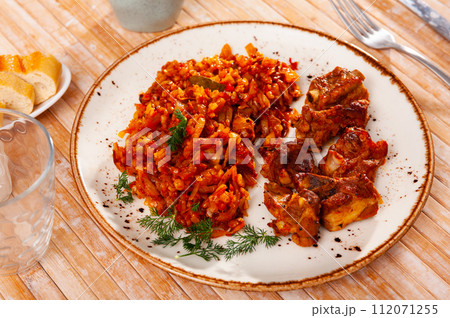 Few fried pork ribs are on plate with side dish of stewed cabbage with pearl barley with sprigs of dill Few fried pork ribs are on plate with side dish of stewed cabbage with pearl barley with sprigs of dill 112071255