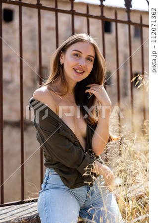 Woman in unbuttoned blouse posing near fence 112071362