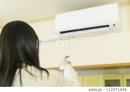 エアコンを操作する女性（リモコンにピント） 112071846