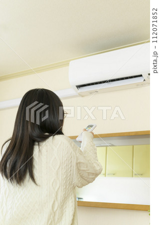 エアコンを操作する寒がっている女性 エアコンを操作する寒がっている女性 112071852