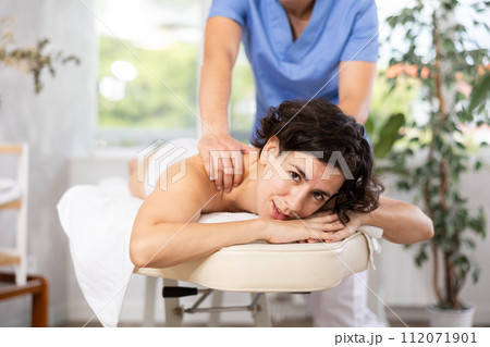 Portrait of woman enjoying relaxing massage by professional masseur Portrait of woman enjoying relaxing massage by professional masseur 112071901