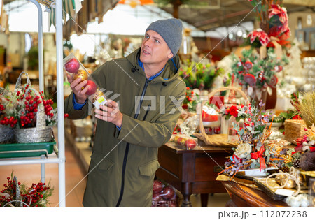 Man selecting christmas decorations in home goods store Man selecting christmas decorations in home goods store 112072238