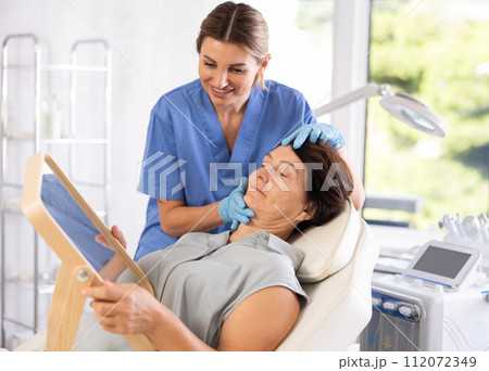 Female aesthetician consulting elderly woman before hardware facial skin treatments Female aesthetician consulting elderly woman before hardware facial skin treatments 112072349