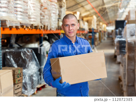 Fulfillment center worker standing and holding carboard box 112072385