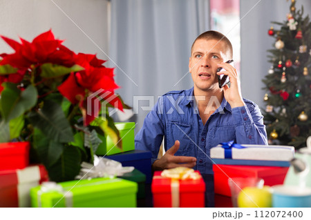 man prepares Christmas gifts and calls on his smartphone 112072400