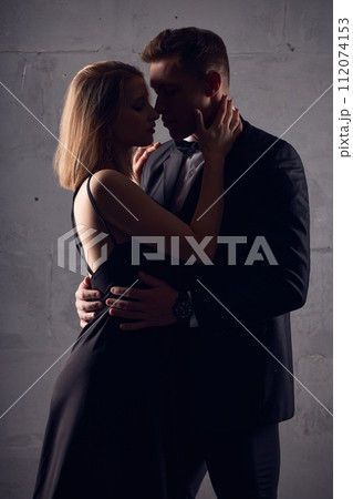 Loving couple teasing each other in black female dress and male black suit Loving couple teasing each other in black female dress and male black suit 112074153