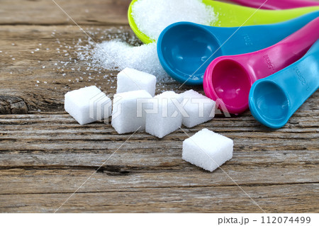 Measuring utensils and spilled sugar on rustic wood 112074499