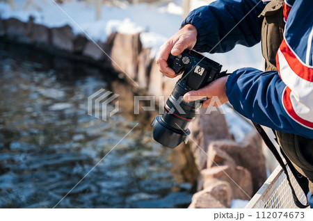 photographer's hand with modern dslr camera photographing nature in winter 112074673