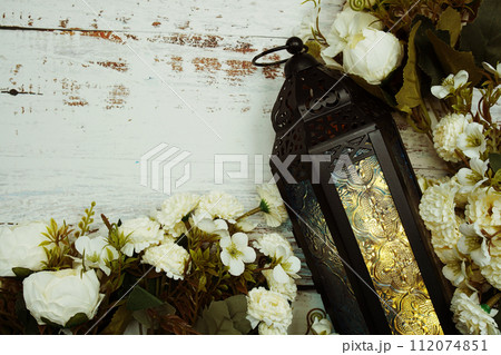 Black Moroccan Arabic lantern with flower on white table background Black Moroccan Arabic lantern with flower on white table background 112074851