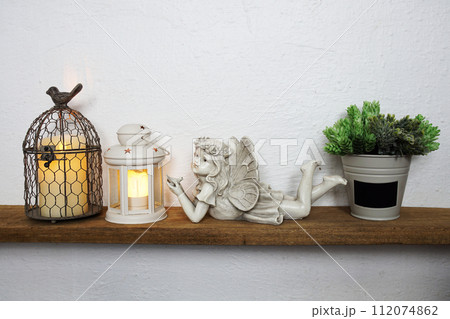 White lantern and Fairy statue Home decoration accessories on wooden shelves White lantern and Fairy statue Home decoration accessories on wooden shelves 112074862