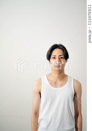 白いバックでポージングをする若いタンクトップの男性 112076911