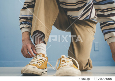 青い背景で黄色い靴を履く若い男性 112077600