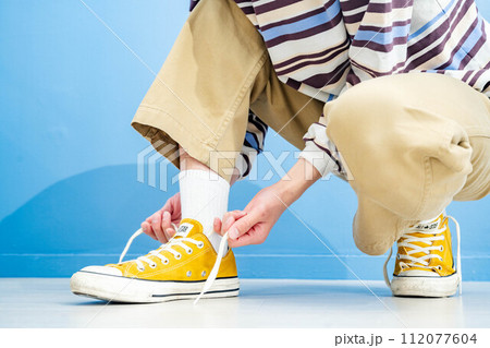 青い背景で黄色い靴を履く若い男性 112077604