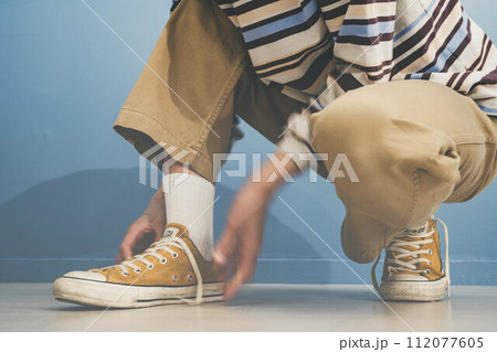 青い背景で黄色い靴を履く若い男性 112077605