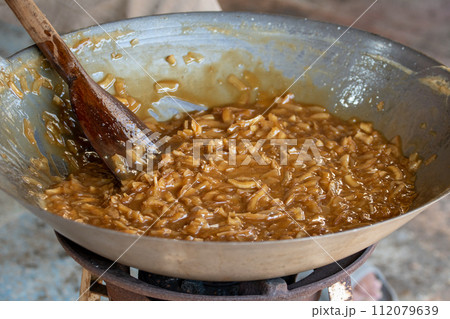 thin coconut flakes fried in sugar syrup thin coconut flakes fried in sugar syrup 112079639