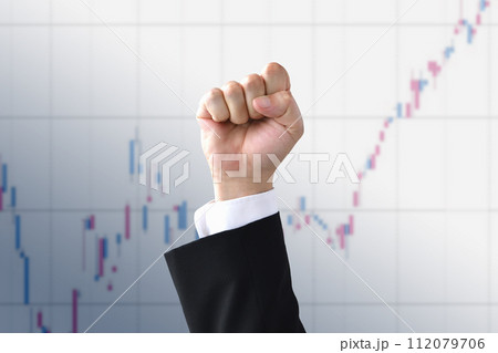 株式チャートの前で突き上げられた拳 112079706