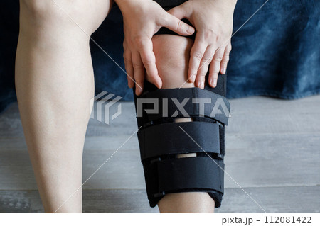 Photo of women leg with knee brace sitting at home 112081422