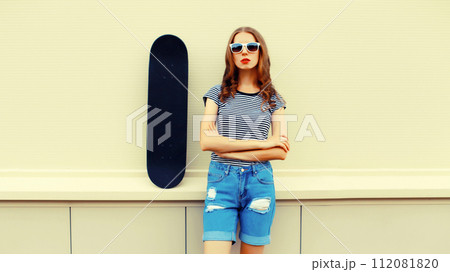Portrait of stylish young woman with skateboard in the city 112081820