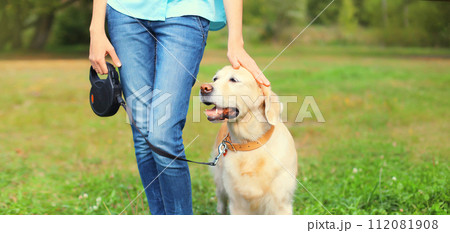 Owner woman walking with her Golden Retriever dog on leash in summer park Owner woman walking with her Golden Retriever dog on leash in summer park 112081908