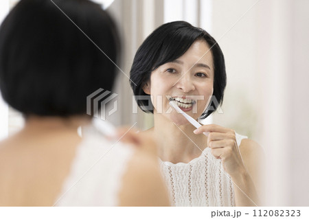 鏡を見ながら歯を磨く50代前半の女性 112082323