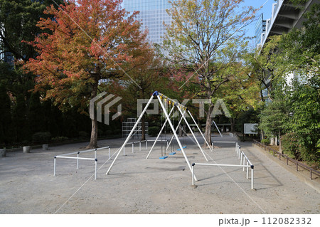 the Empty Playground Slide in a Green Park with Urban City Buildings 112082332
