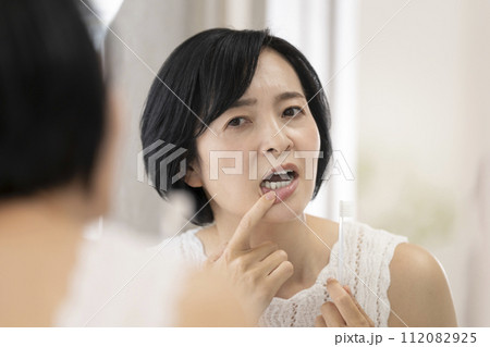 歯磨きをしながら歯茎を気にするアラフィフの女性 112082925