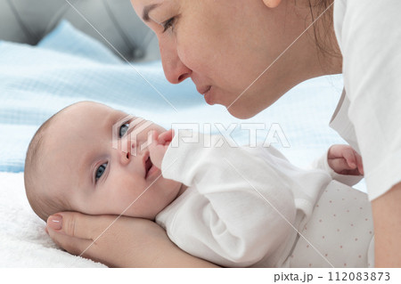 Mom leans over and gently reaches out to kiss the newborns cheek 112083873