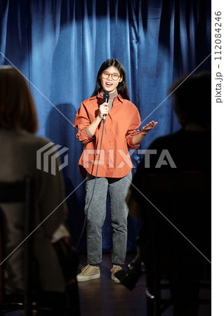 Comedian standing against blue curtains Comedian standing against blue curtains 112084246