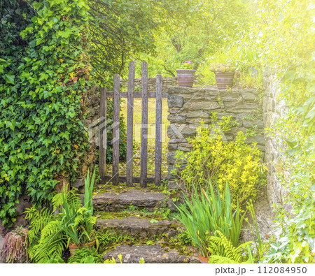 Wooden gate in a stone wall on a farm on sunlight 112084950