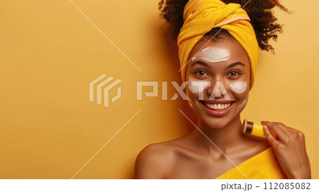 Joyful woman applying facial cream 112085082