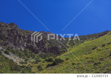 Rocky mountains with green grass under blue sky in summer 112085715