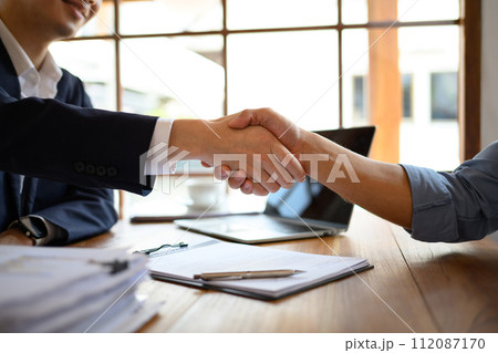 Businesspeople shaking hands after closing deal or successful negotiations at meeting Businesspeople shaking hands after closing deal or successful negotiations at meeting 112087170