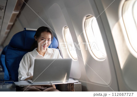 Successful young asian business woman sits in airplane cabin plane and working from anywhere. Flying at first class 112087727