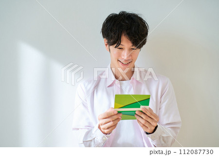 通帳を眺めている若い男性 通帳を眺めている若い男性 112087730