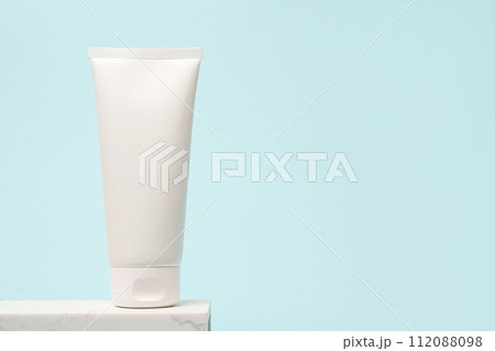 White cosmetic tube staying on the stone podium, blue background with copy space White cosmetic tube staying on the stone podium, blue background with copy space 112088098