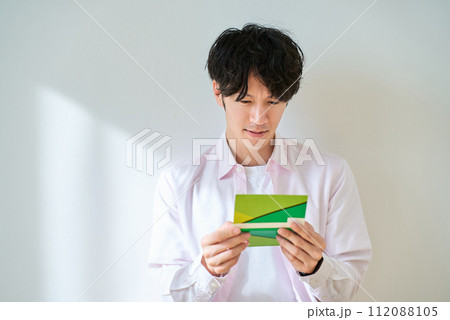 通帳を見て、がっかりする若い男性 通帳を見て、がっかりする若い男性 112088105