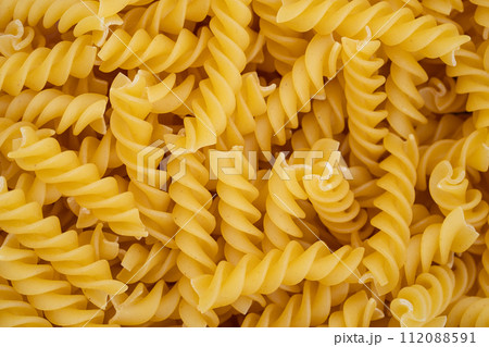 Highly detailed close-up of uncooked fusilli pasta showcasing the texture and shape of this classic Italian ingredient. 112088591