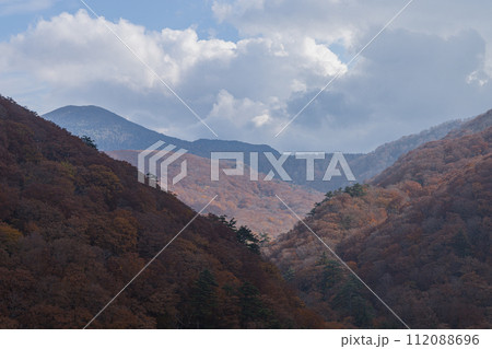 日本　青森県青森市の十和田八幡平国立公園内にある城ヶ倉大橋から見える城ヶ倉渓流の紅葉と八甲田連峰 112088696