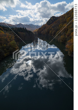 日本 青森県中津軽郡の大川白神橋から見える大川の立ち枯れと鏡面に映った紅葉と空 日本 青森県中津軽郡の大川白神橋から見える大川の立ち枯れと鏡面に映った紅葉と空 112088733