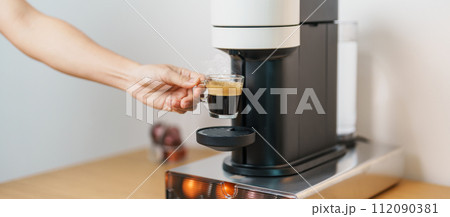 hand making Espresso Coffee by Coffee Maker Machine with Capsule of roasted coffee bean on wood table bar. Daily beverage drink at Home, Apartment and Office concept hand making Espresso Coffee by Coffee Maker Machine with Capsule of roasted coffee bean on wood table bar. Daily beverage drink at Home, Apartment and Office concept 112090381
