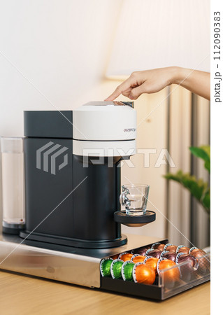 hand making Espresso Coffee by Coffee Maker Machine with Capsule of roasted coffee bean on wood table bar. Daily beverage drink at Home, Apartment and Office concept hand making Espresso Coffee by Coffee Maker Machine with Capsule of roasted coffee bean on wood table bar. Daily beverage drink at Home, Apartment and Office concept 112090383