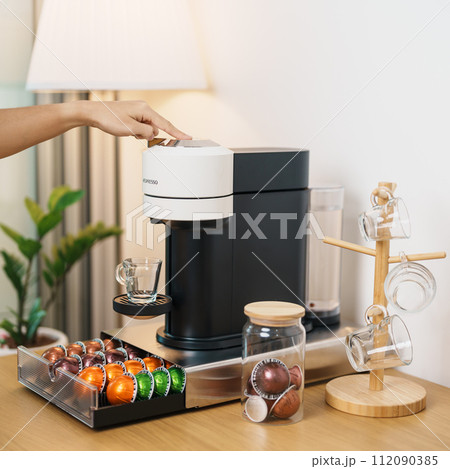 hand making Espresso Coffee by Coffee Maker Machine with Capsule of roasted coffee bean on wood table bar. Daily beverage drink at Home, Apartment and Office concept hand making Espresso Coffee by Coffee Maker Machine with Capsule of roasted coffee bean on wood table bar. Daily beverage drink at Home, Apartment and Office concept 112090385